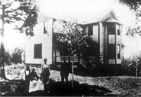 Fred & Carrie Hanks standing in front of their home on the Hanks homestead acquired by Elijah Hanks